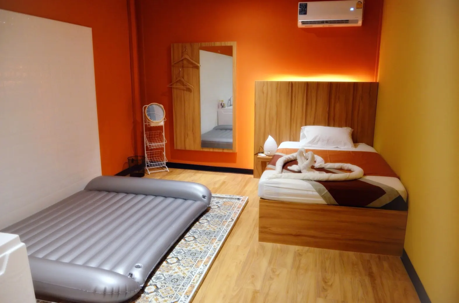 Bath room with a grey air mat on a patterned rug and a made-up bed