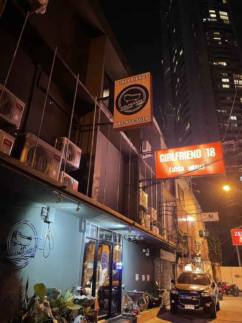 The shop front at night with its lit signs and phone number