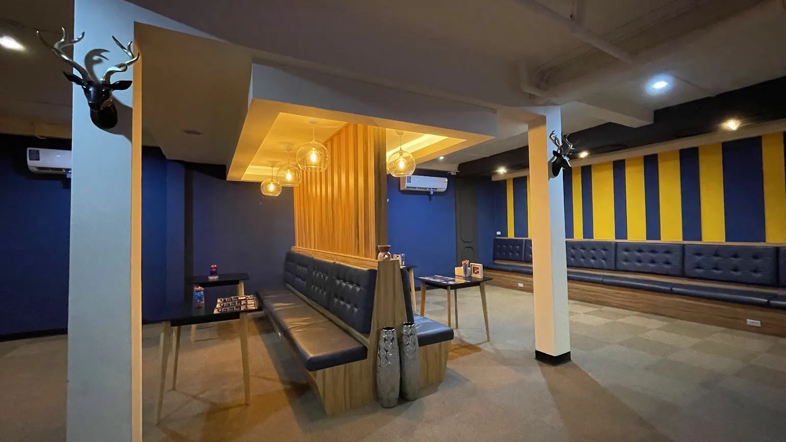 The upstairs lounge with blue tufted benches, wooden slat screen and warm pendant lights