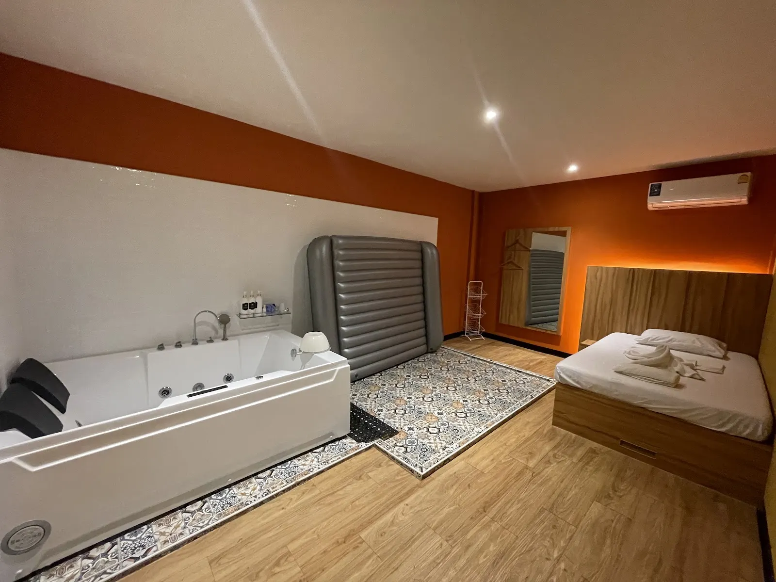 VIP room with a white jet bathtub, an air mat and a bed against orange walls